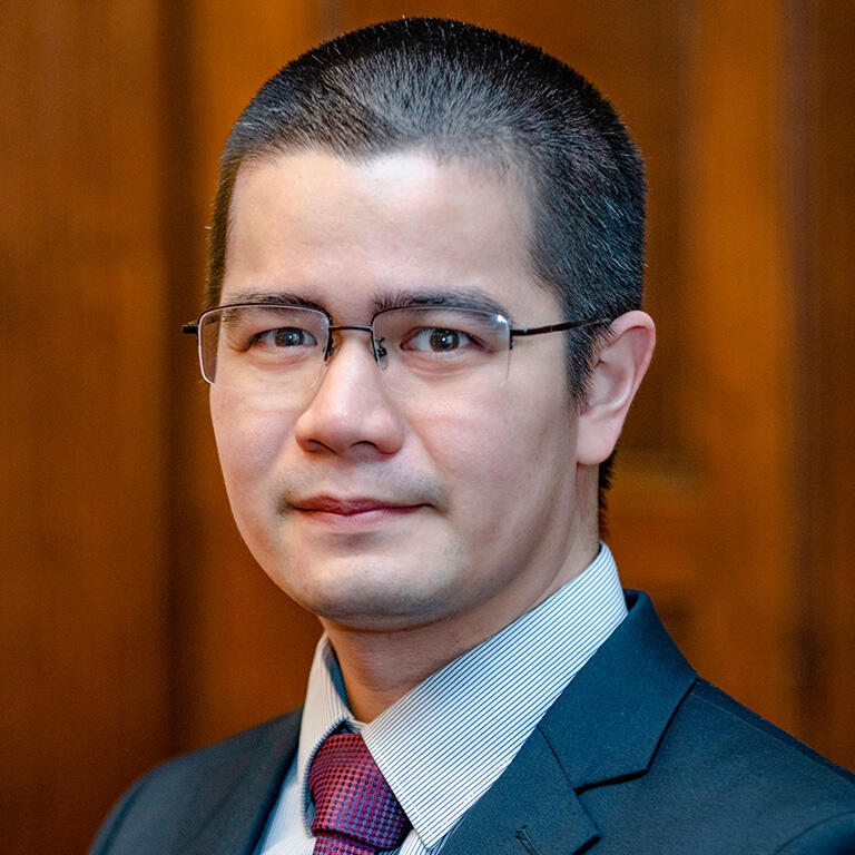 professor jose eos trinidad wearing white top gray tie dark blue suit jacket smiling at camera
